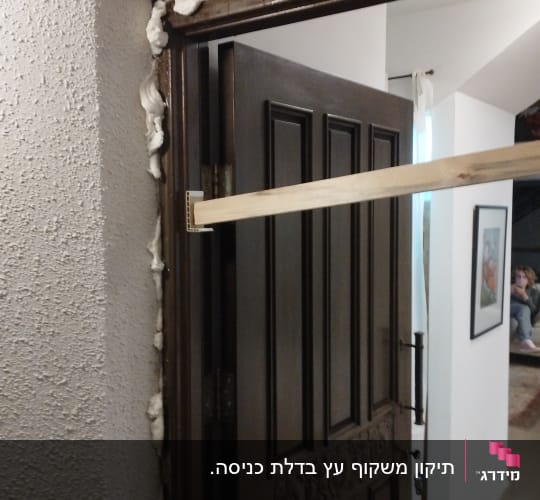 דלת עץ פתוחה עם קצף בידוד סביב המשקוף